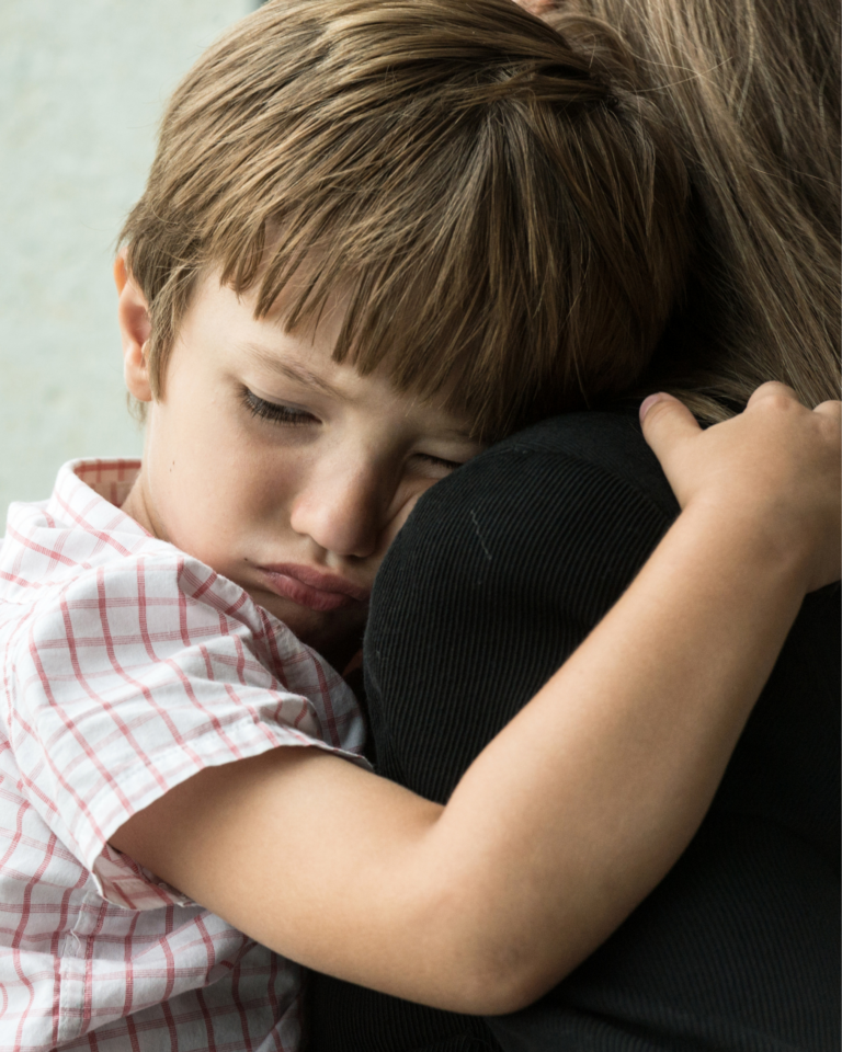 Image of a child looking upset in the arms of their parent