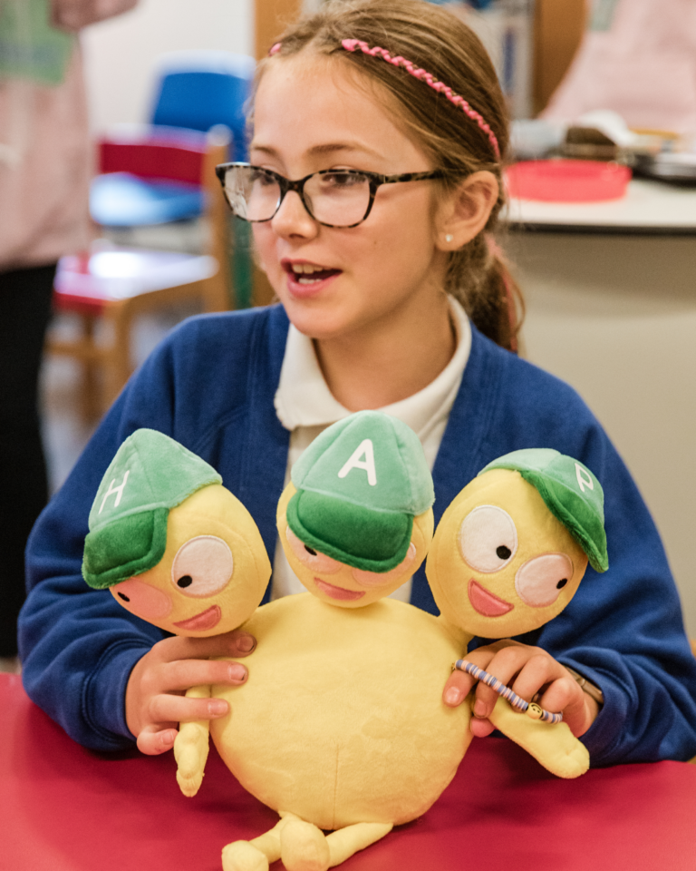 Child that attends a myHappymind school holding the Team HAP plush toy